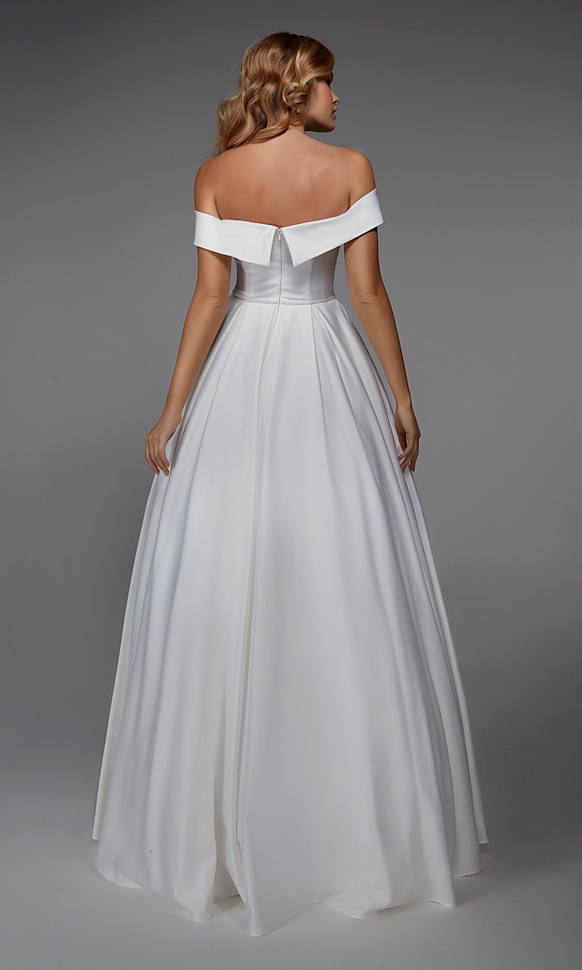 A woman faces away, wearing the Long White Dress: Alyce 7023—an off-the-shoulder evening gown with a fitted bodice and full skirt—set against a plain gray background.